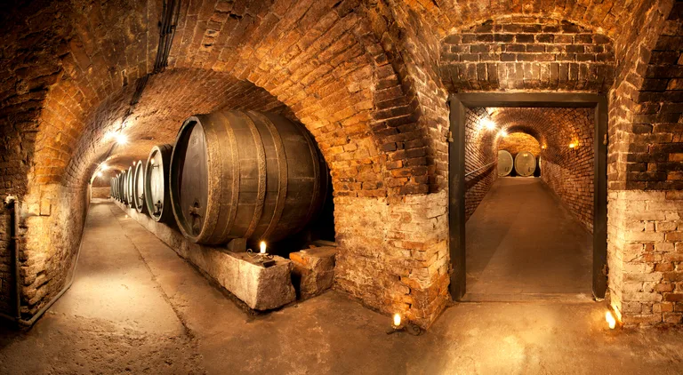 A candlelit old cellar with a great oak cask