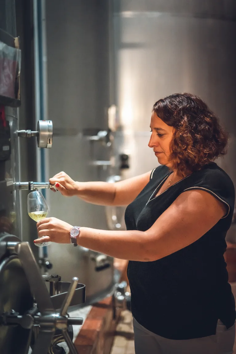 A Wolfberger winemaker drawing a sample from a stainless steel vat.